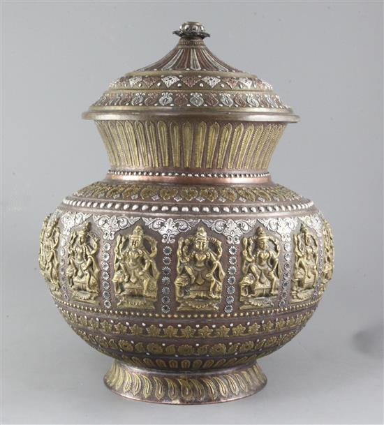 An Indian copper Ganga-Jumna Lota, overlaid in white metal and brass with deities etc, with brass cover overlaid white metal and copper